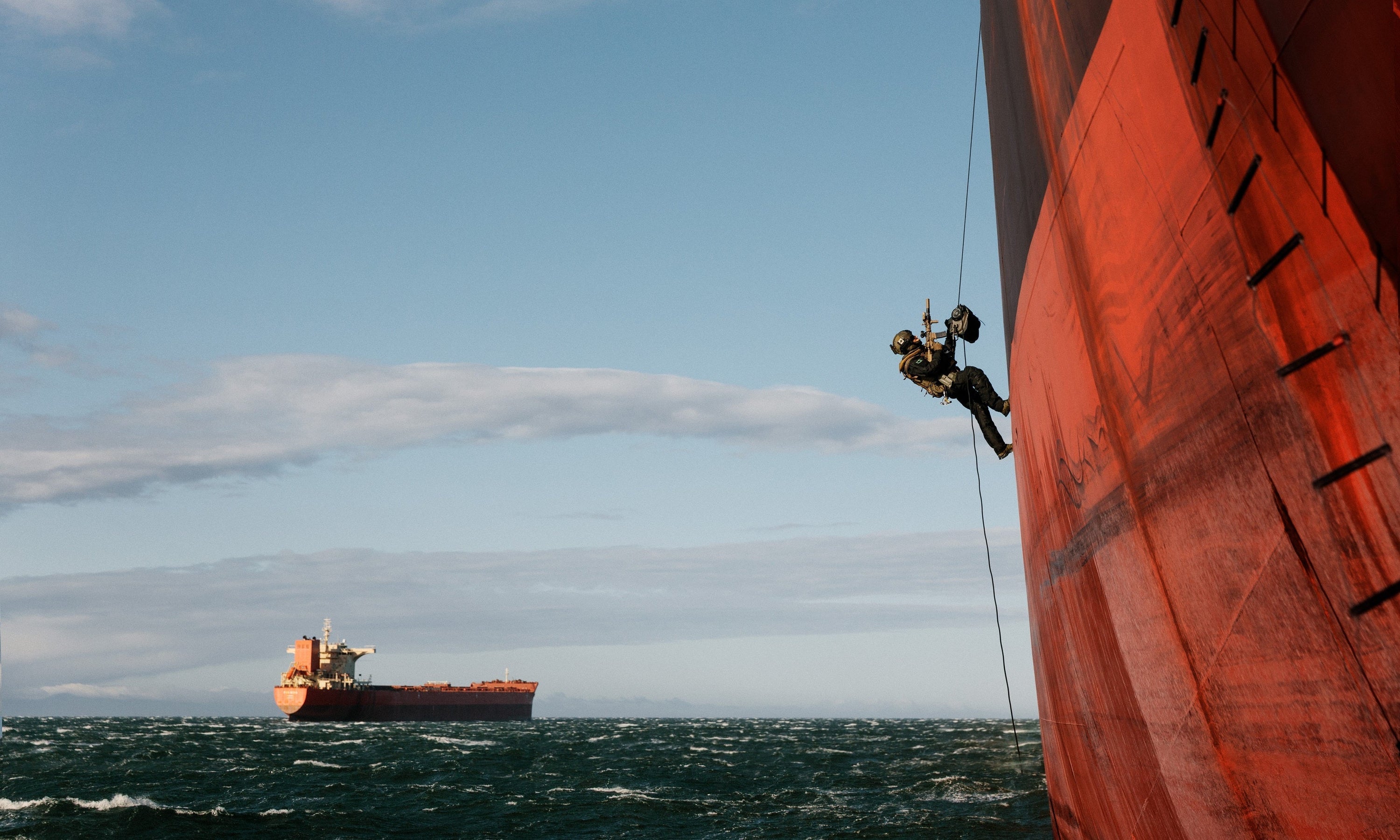 man scaling the side of a cargo ship