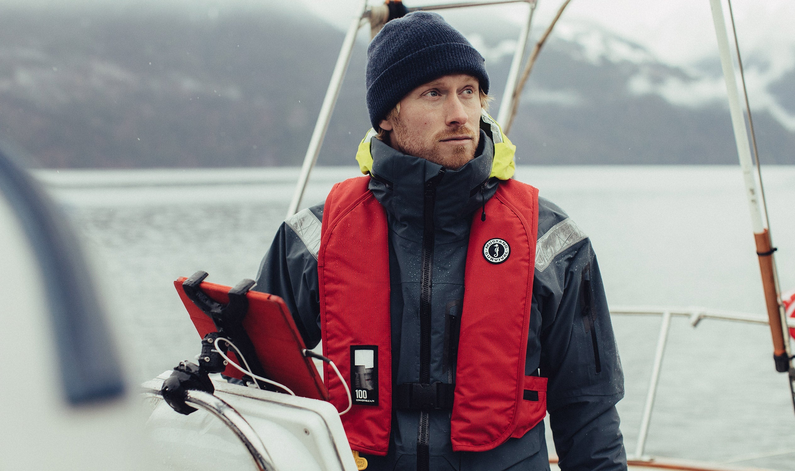 A man on a sailing boat wearing a MIT 100 Convertible Automatic / Manual Inflatable PFD from Mustang Survival