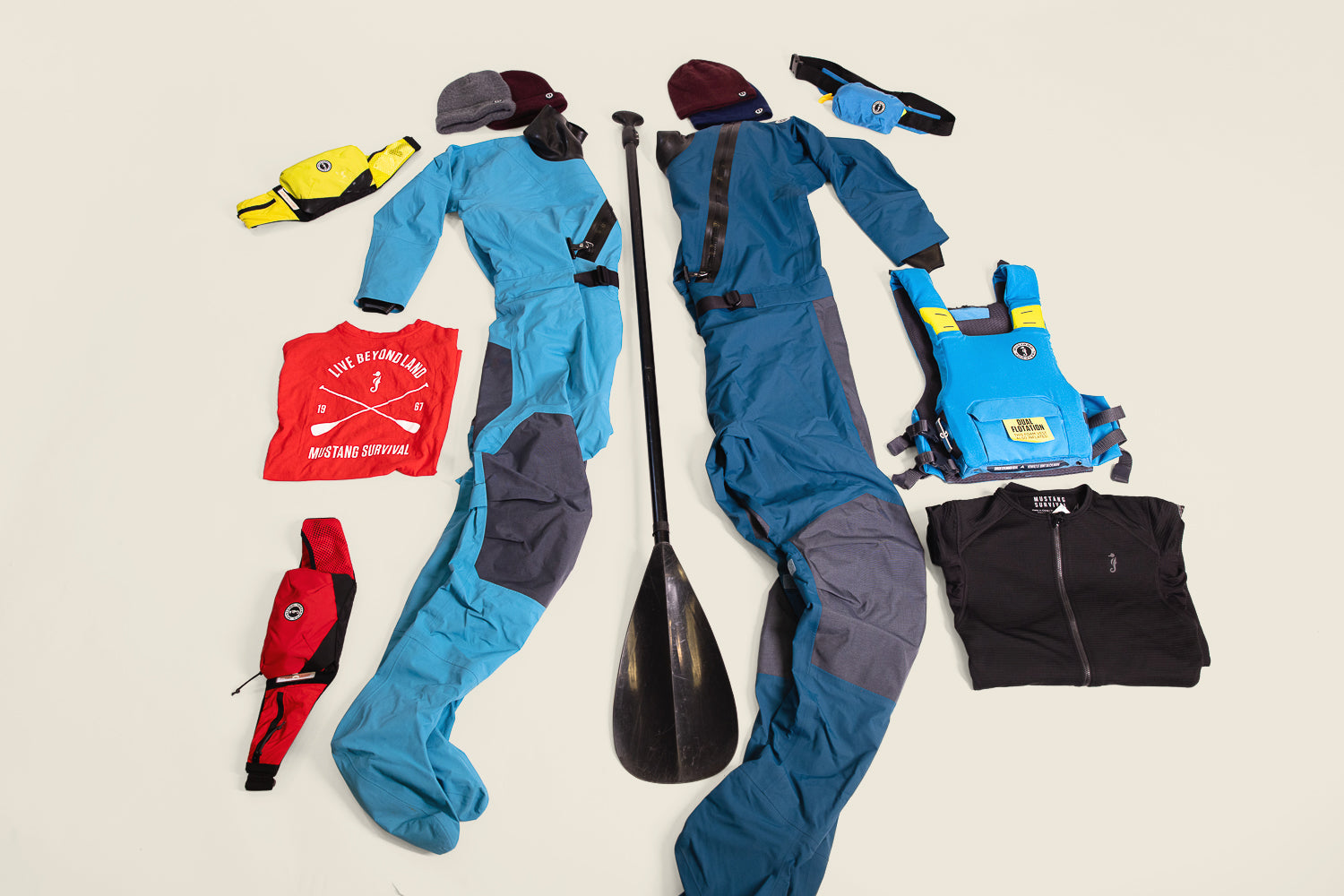 Mustang Survival paddling gear laid out for holiday gifts for paddlers, featuring dry suits, PFDs, and accessories.