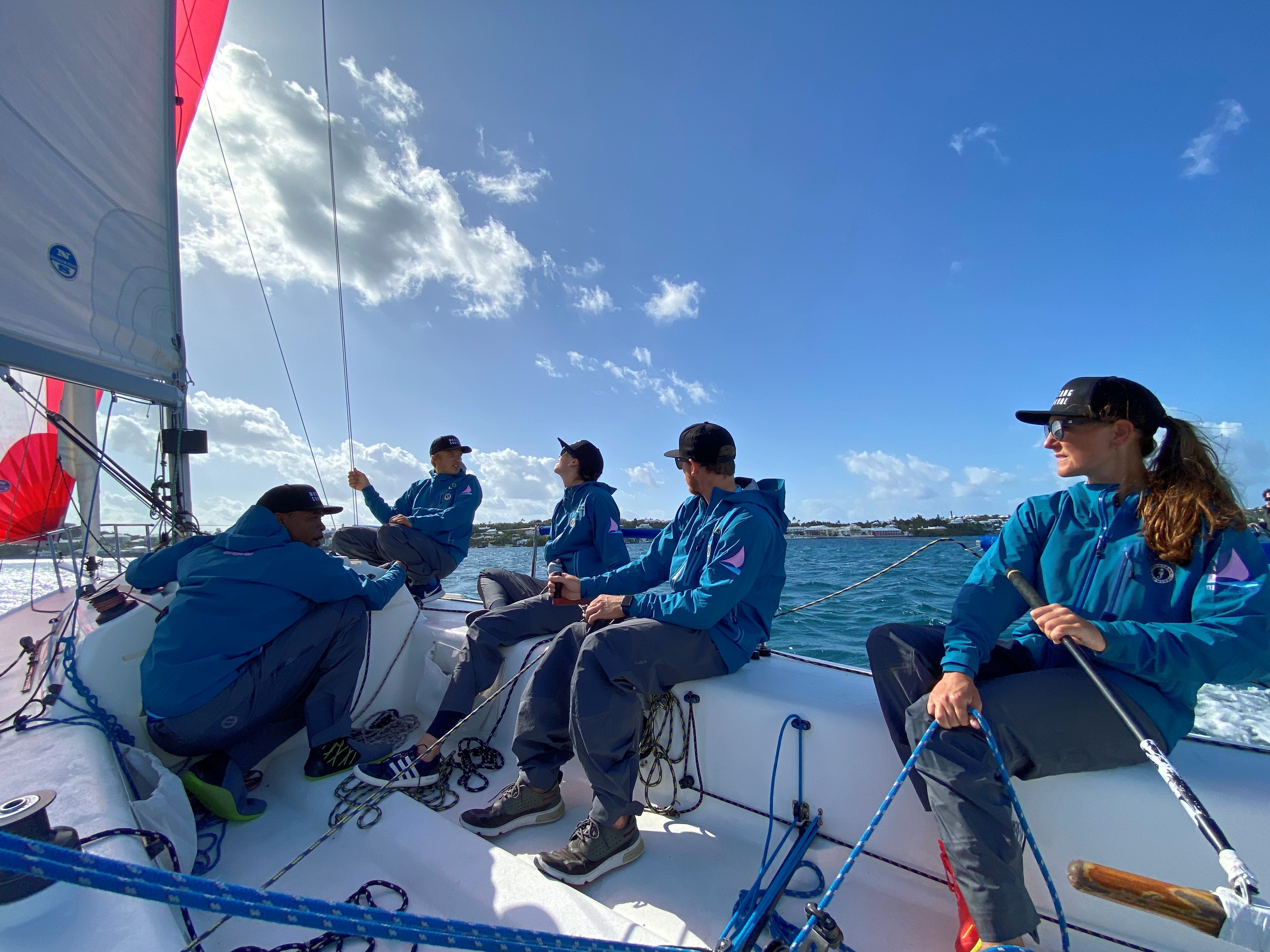 5 crew members on a sailboat on a clear day