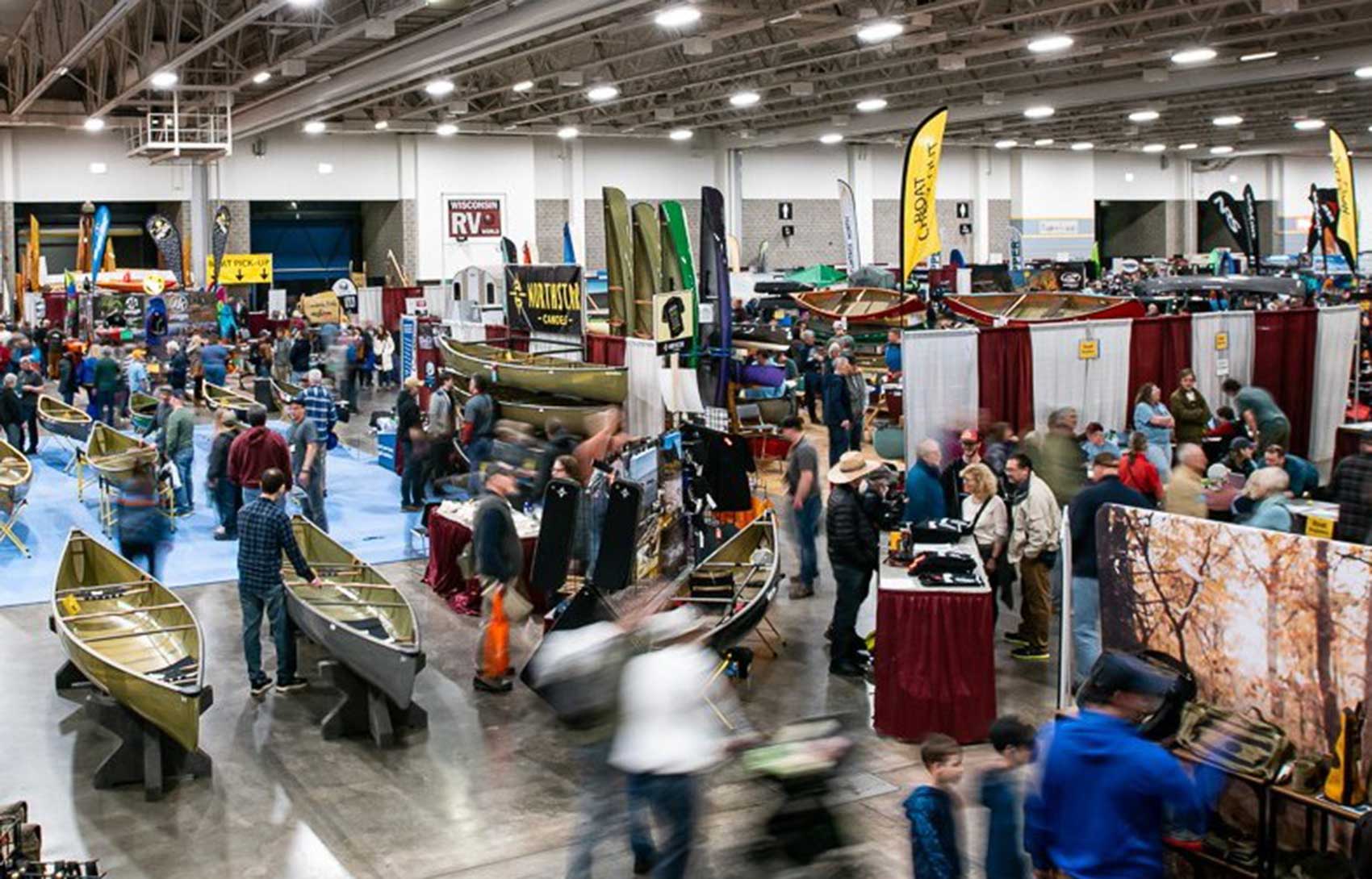 Large indoor event with people and booths at a boating convention.