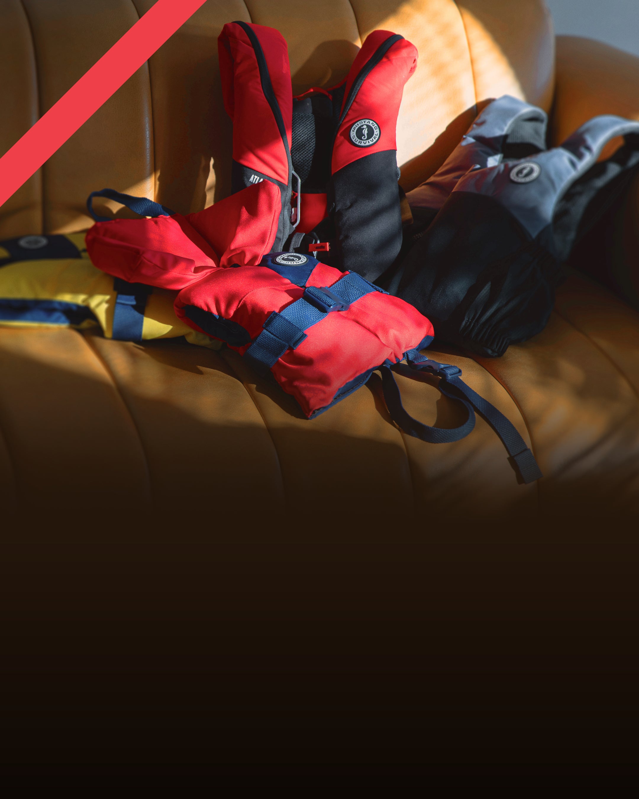 Mustang Survival PFDs and gear laid out for Holiday Gift Guide 2025 on a couch, featuring gifts for sailors, anglers, paddlers, and boaters.